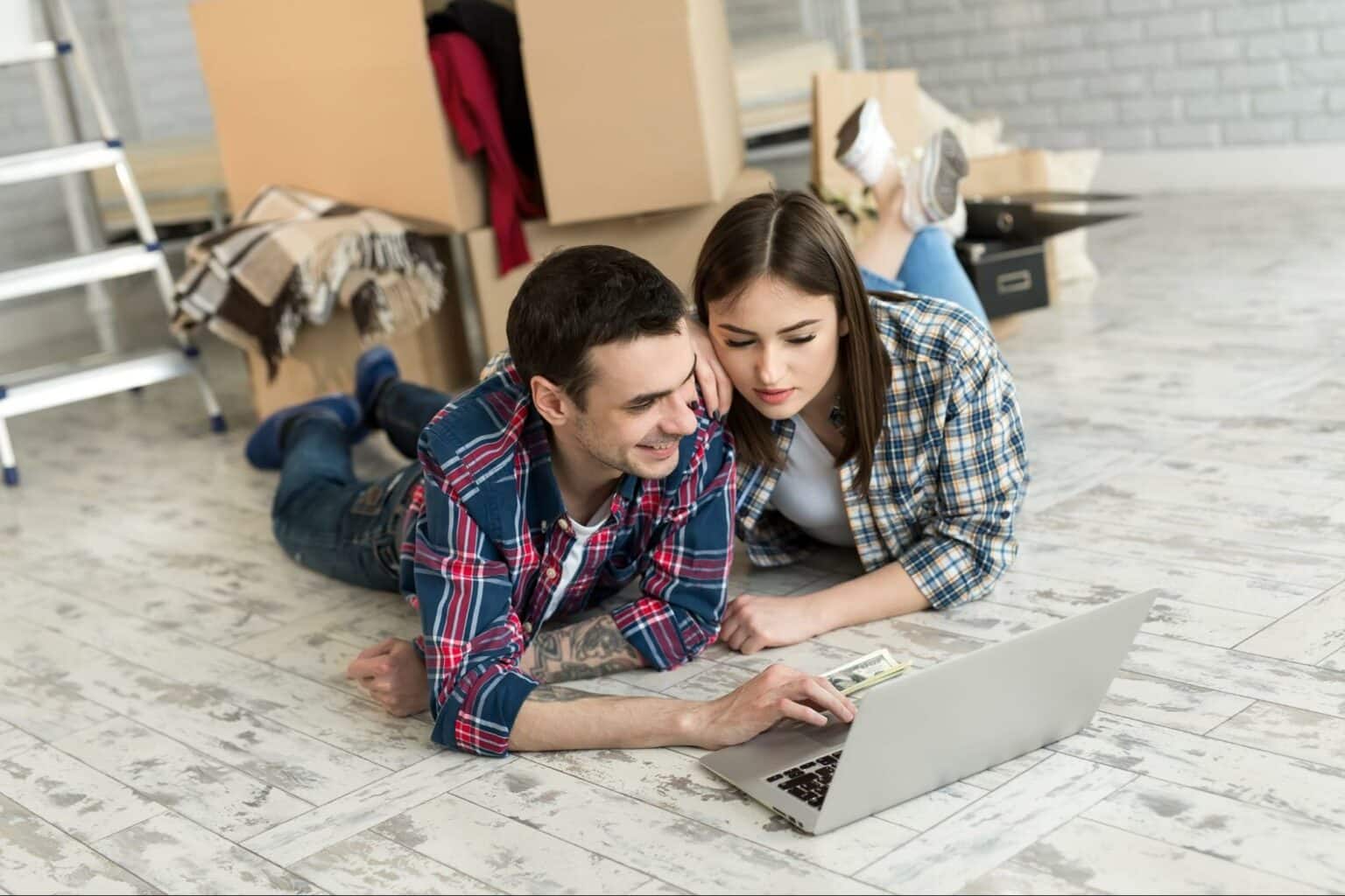 Couple using a laptop together while settling into their new home.