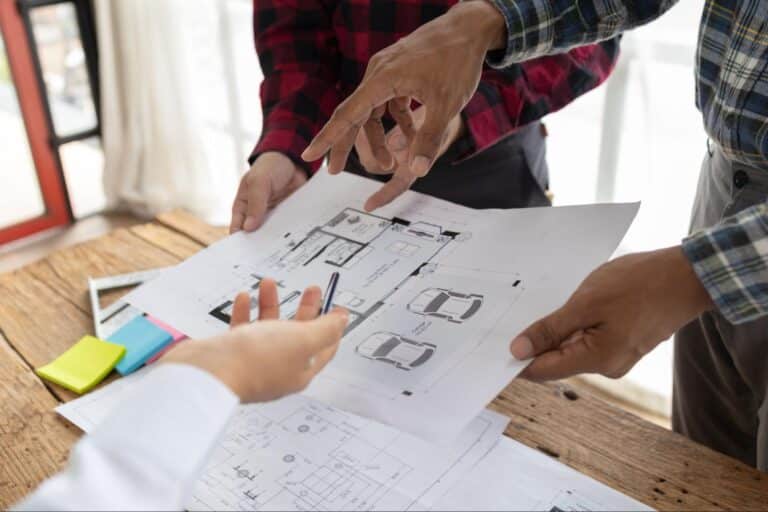 People collaborating on architectural designs and concepts, pointing at sketches and plans.
