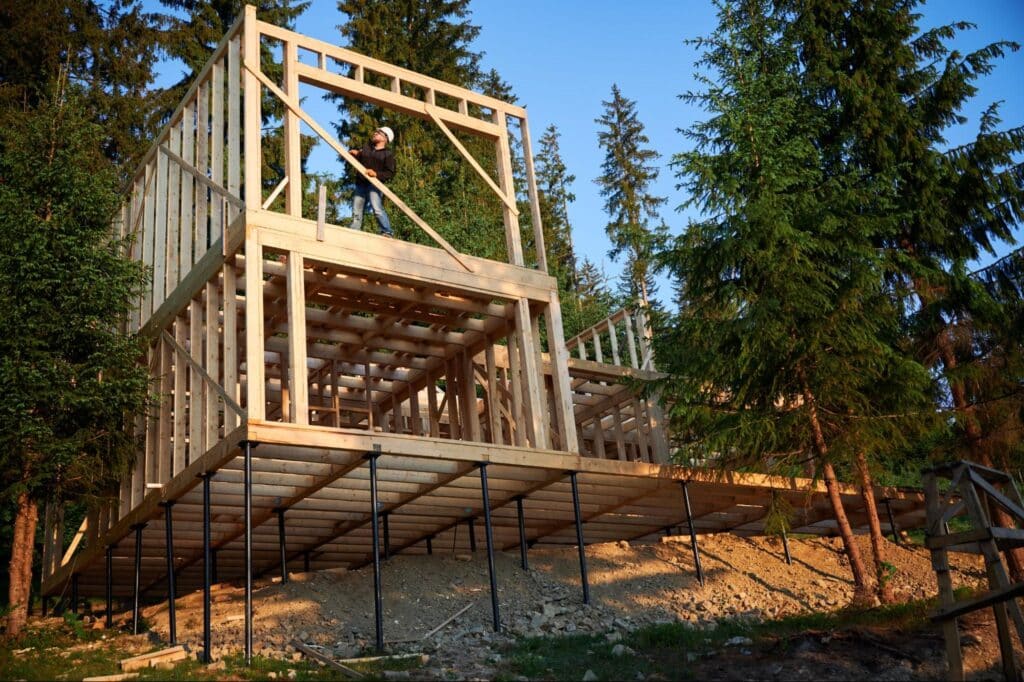 Wooden structure under construction surrounded by trees in a serene landscape.
