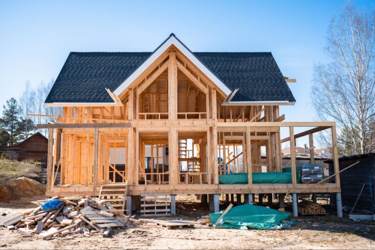 Newly built home under construction with wooden framing and a clear blue sky.