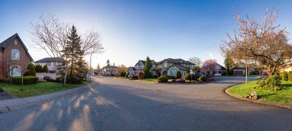 Sunset over a serene suburban street with beautiful homes and lush greenery.