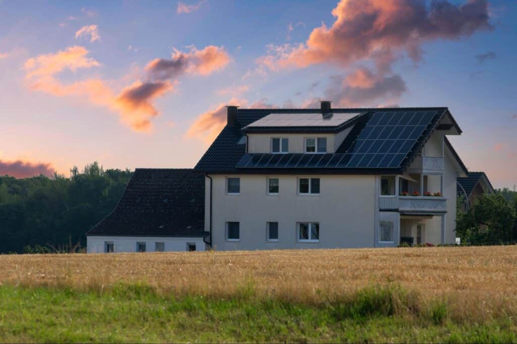 Sustainable home with solar panels under a stunning sunset sky.