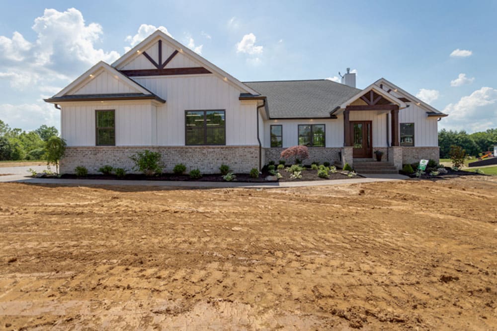 Modern home exterior featuring lush landscaping on a newly graded lot.