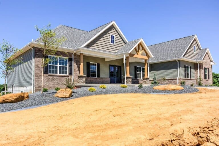 Modern home exterior with landscaping, featuring stone accents and a vibrant blue sky.