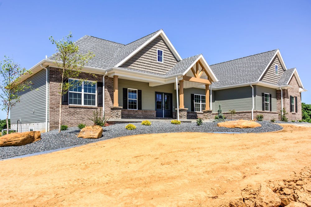 Modern home exterior with landscaping, featuring stone accents and a vibrant blue sky.