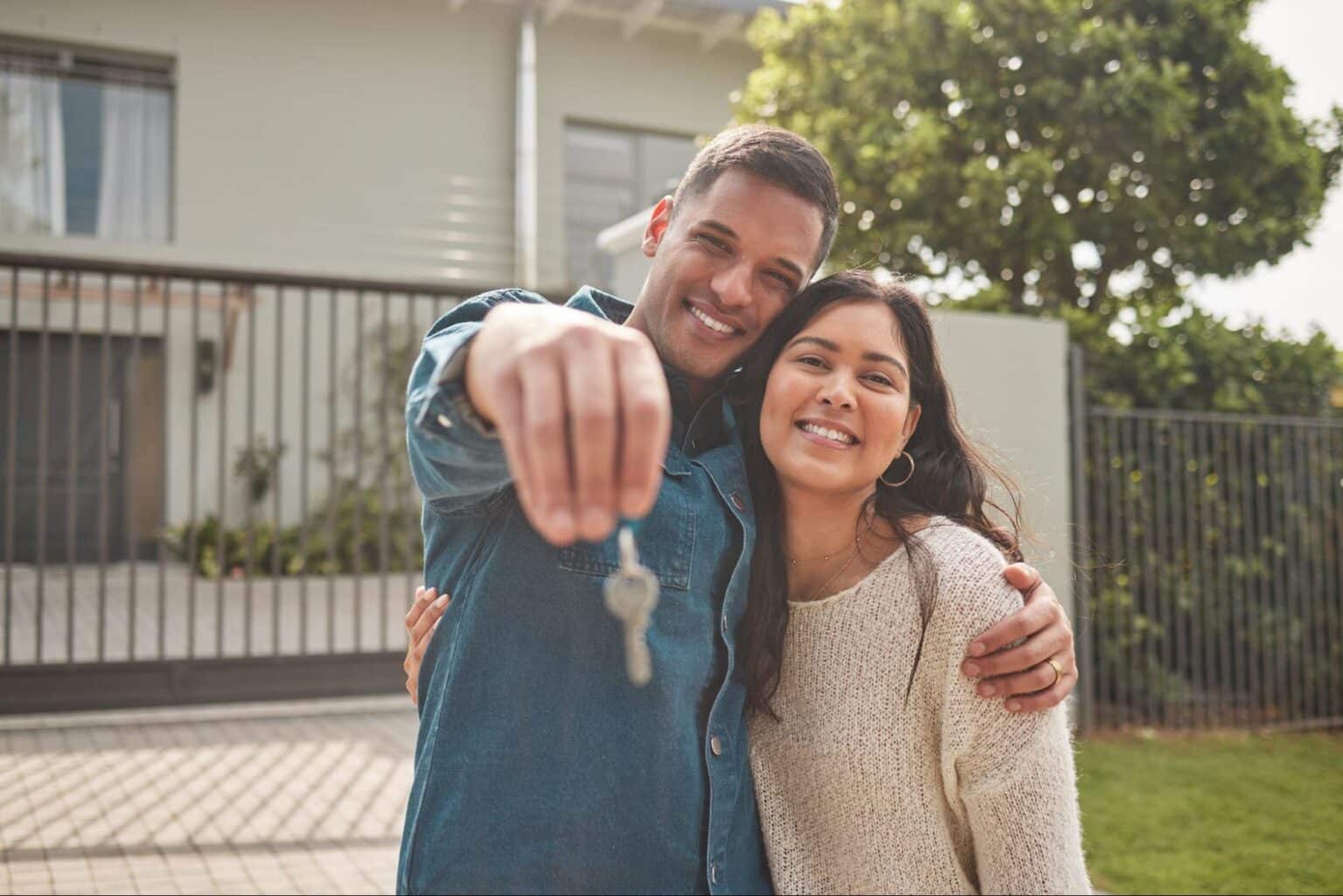 Happy couple proudly holding keys to their first home.