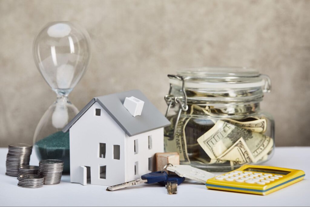 Model house, money, and calculator representing real estate investment and financial planning.