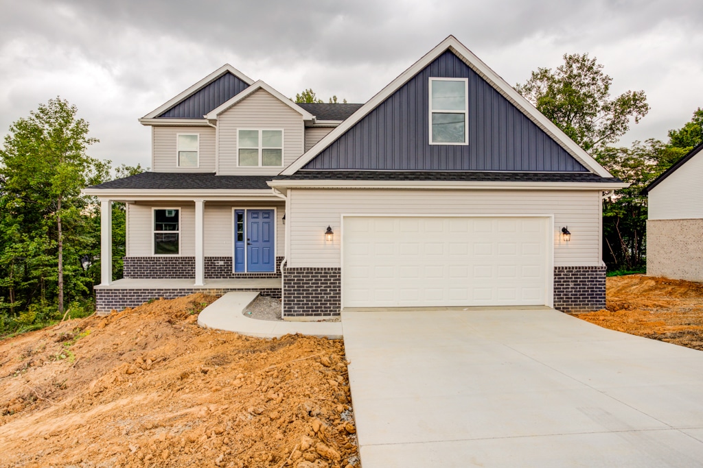 Modern home featuring blue accents and a spacious driveway in a tranquil landscape.
