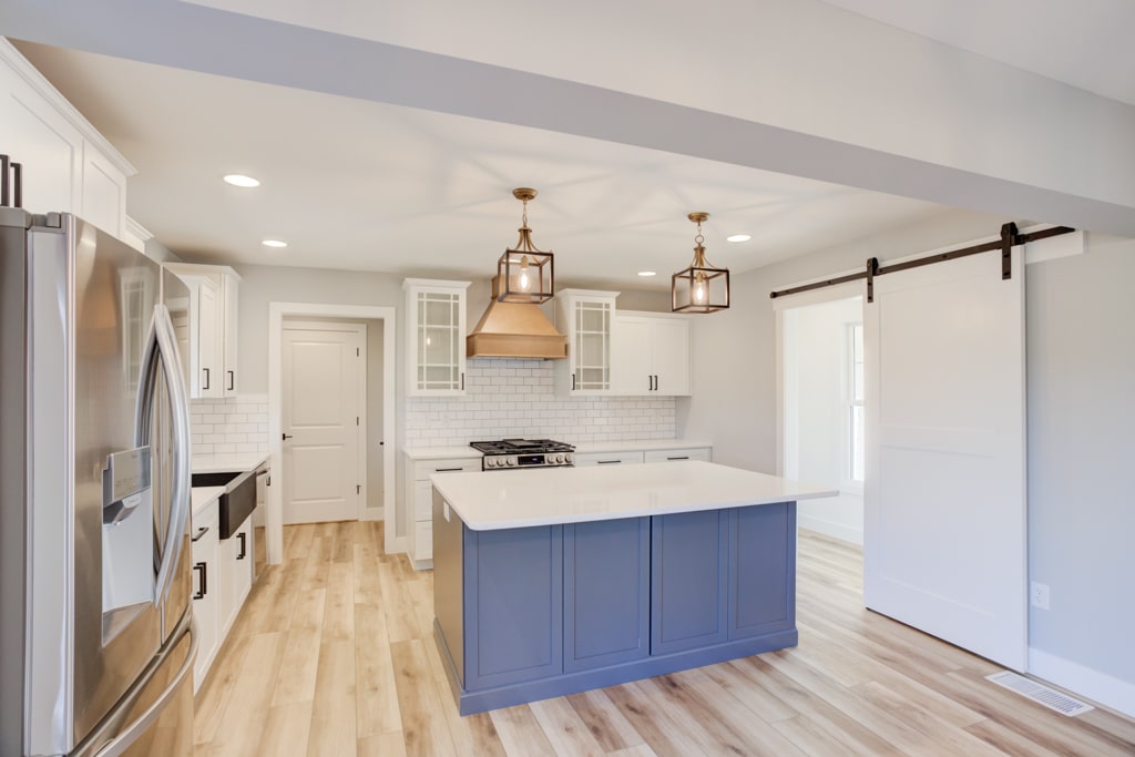 Elegant modern kitchen featuring a bright blue island and stylish pendant lighting.