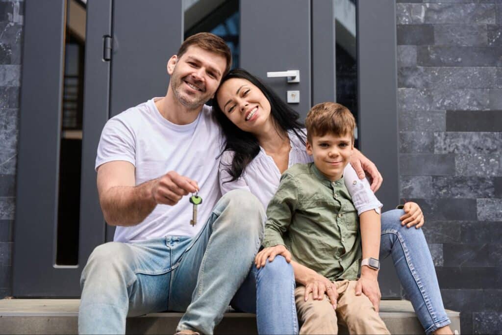 Joyful family celebrating their new home with keys on the front steps.