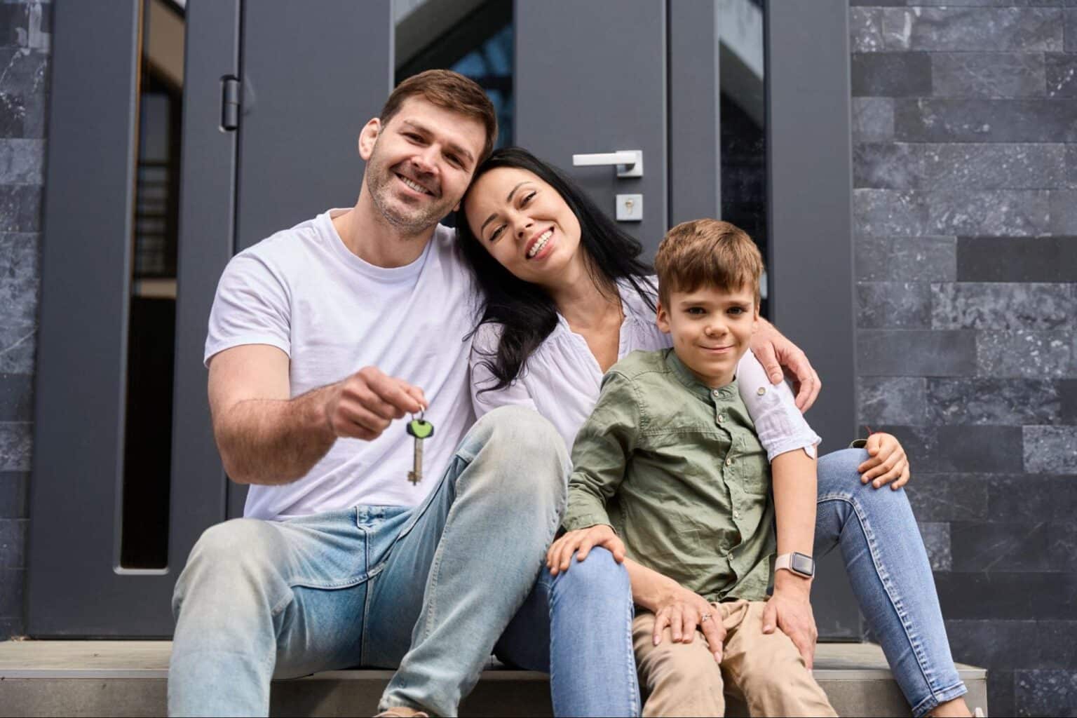 Joyful family celebrating their new home with keys on the front steps.