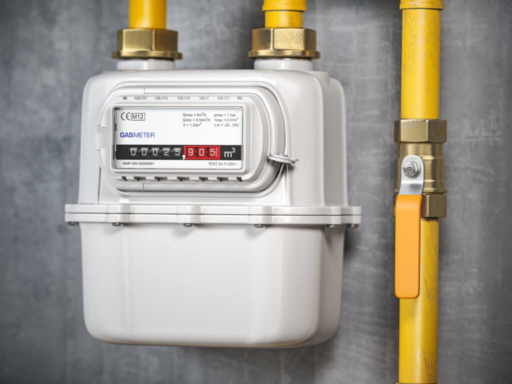 Natural gas meter mounted on a wall with yellow tubes and display readings.