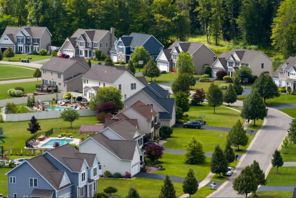 Aerial view of charming suburban homes with lush green lawns and tree-lined streets.