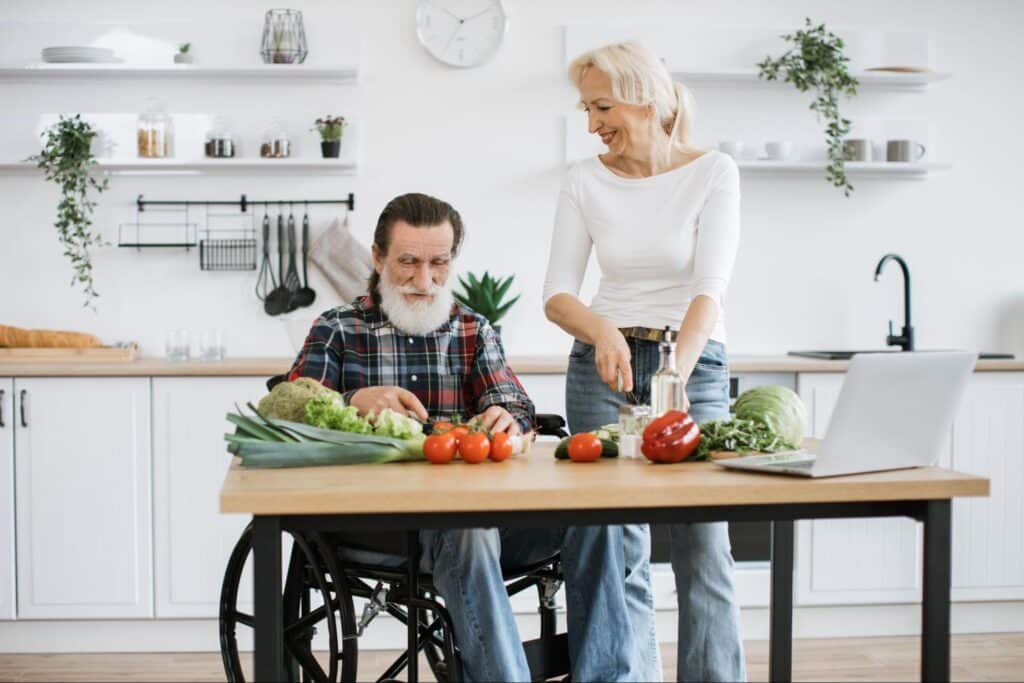 Senior man cooking with caregiver in modern kitchen, enjoying quality time together.