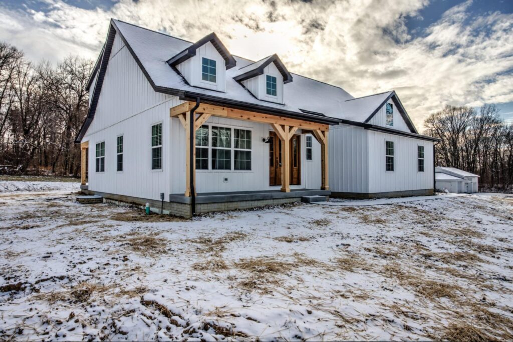 Modern farmhouse surrounded by a winter landscape, capturing idyllic snowy serenity.
