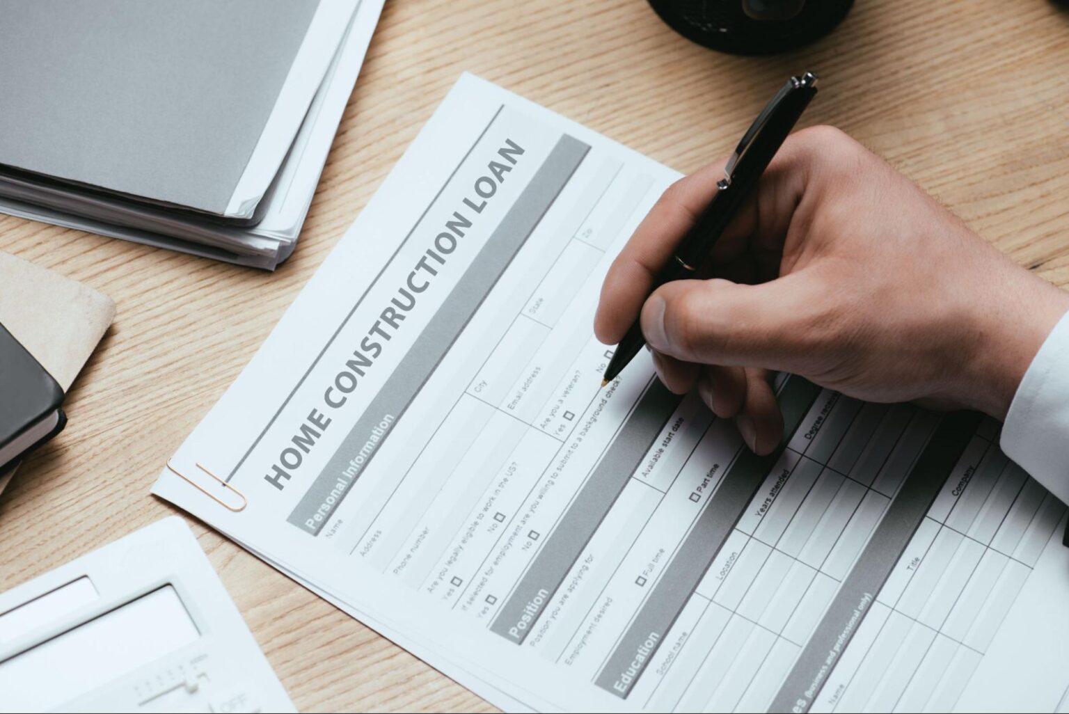 Filling out a home construction loan application on a wooden desk.