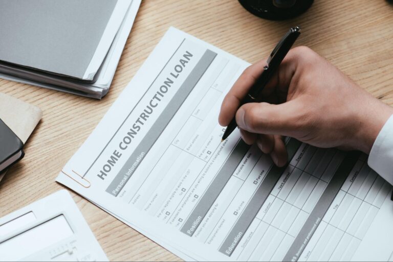 Filling out a home construction loan application on a wooden desk.