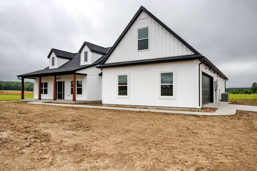 Modern farmhouse with sleek black accents and large open yard space.