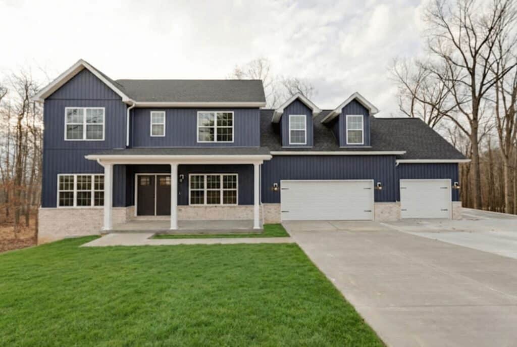 Modern blue home with a large lawn in a peaceful, natural setting.