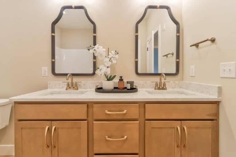 Elegant bathroom vanity featuring mirrors and decorative flowers for a stylish touch.