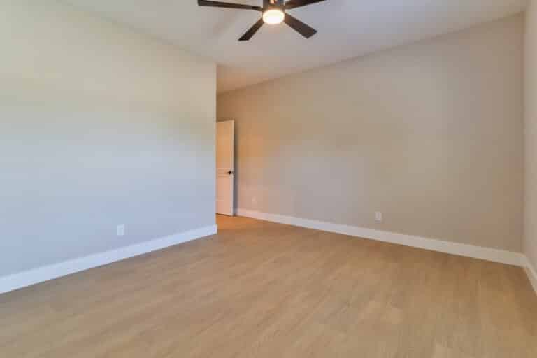 Spacious, empty room interior with wooden flooring and natural light from an open door.