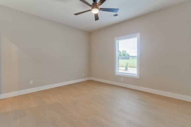 Modern empty room with wood flooring and natural light from the window.