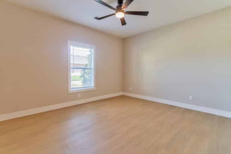 Bright empty room with a window and ceiling fan, perfect for personalization.