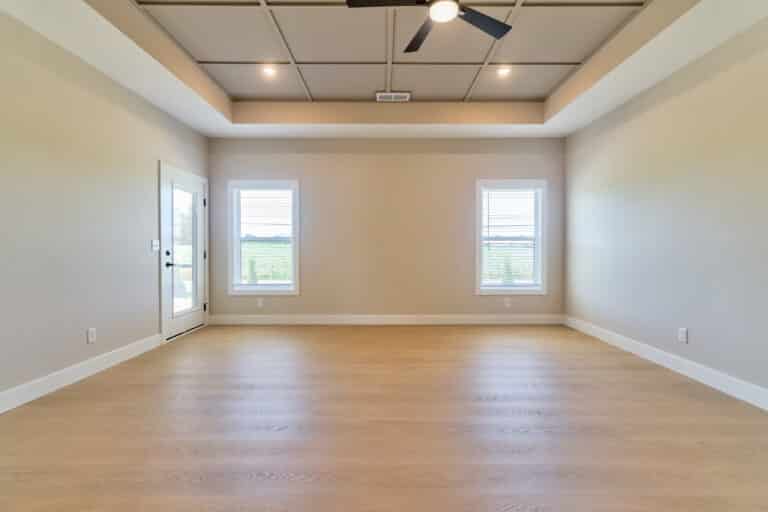 Bright, spacious empty room with windows and warm wooden flooring for versatile designs.