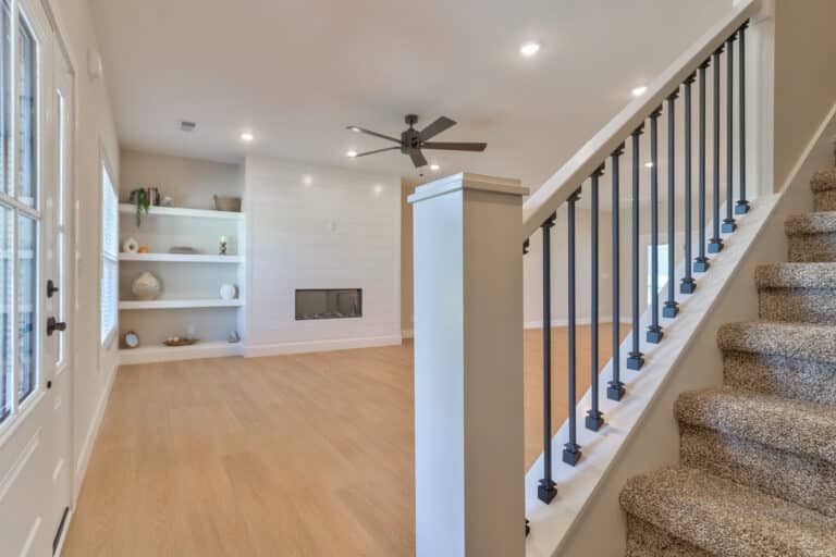 Spacious living room featuring stairs, modern decor, and natural light.