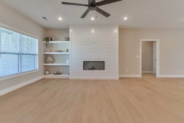 Stylish minimalist living room featuring a modern fireplace and natural wood floors.