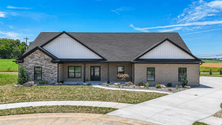 Modern home with stylish design, surrounding landscaping, and a beautiful blue sky.