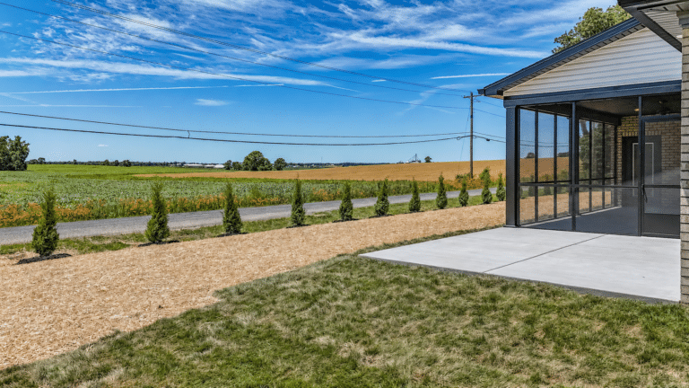 Scenic view from a screened porch overlooking lush fields and clear blue skies.
