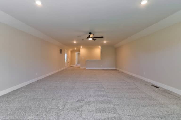 Bright and airy spacious living room with modern ceiling fan and plush carpet.