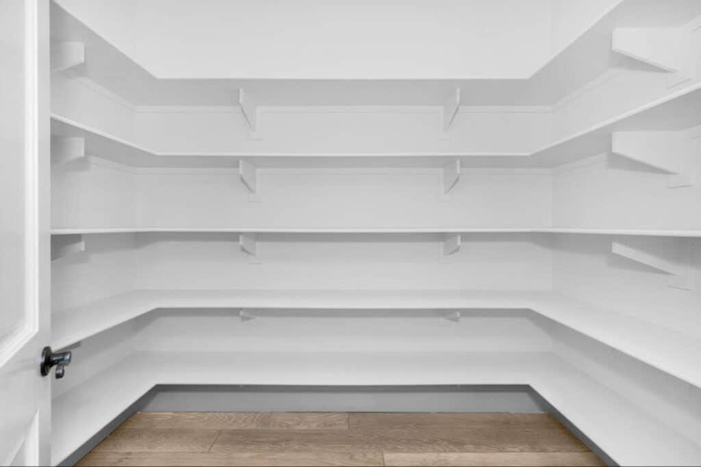 Bright and spacious white pantry with open shelves for organizing food and supplies.