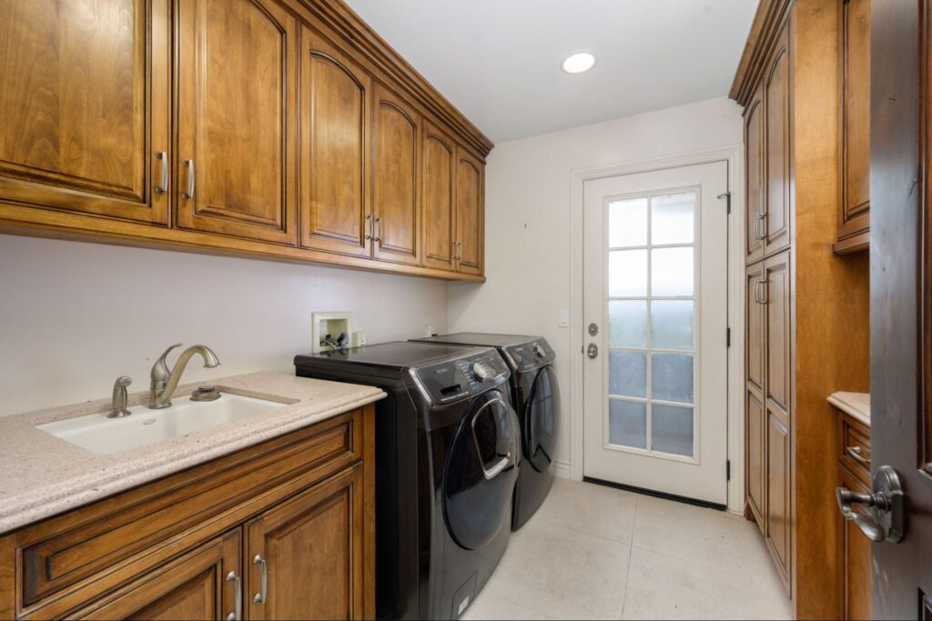 Efficient laundry room with sleek appliances and stylish wooden cabinets for optimal organization.