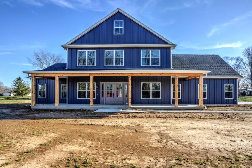 Charming blue farmhouse with a spacious porch and inviting front yard.