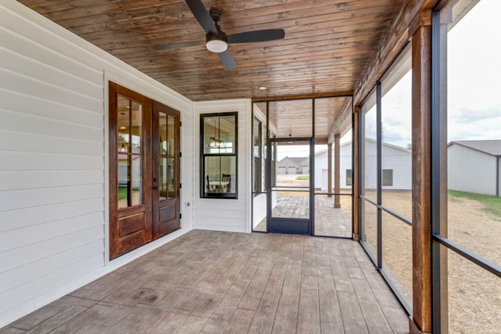 Elegant screened porch with wooden doors and a stylish ceiling fan.