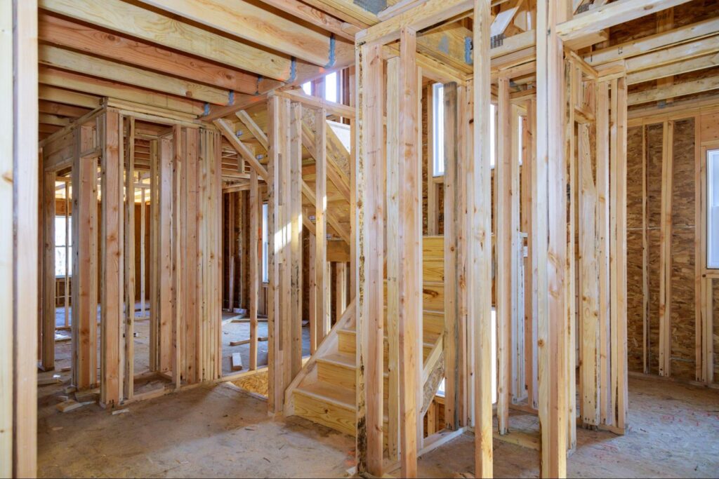 Modern home interior under construction with exposed wood framing and a staircase.