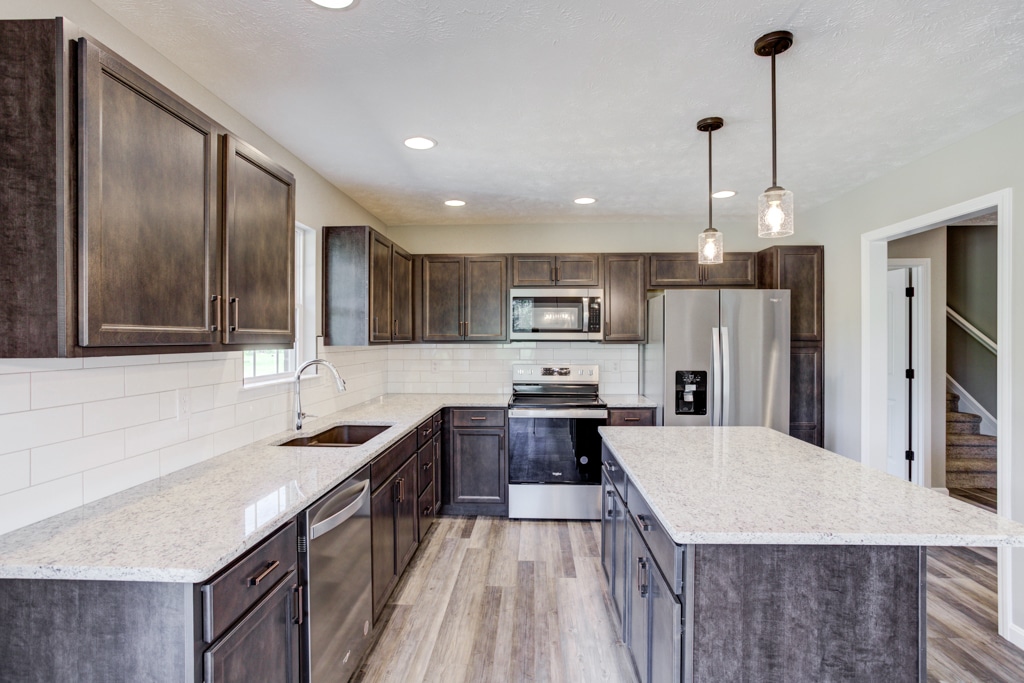 Sleek kitchen featuring dark cabinets, granite counters, and modern stainless steel appliances.