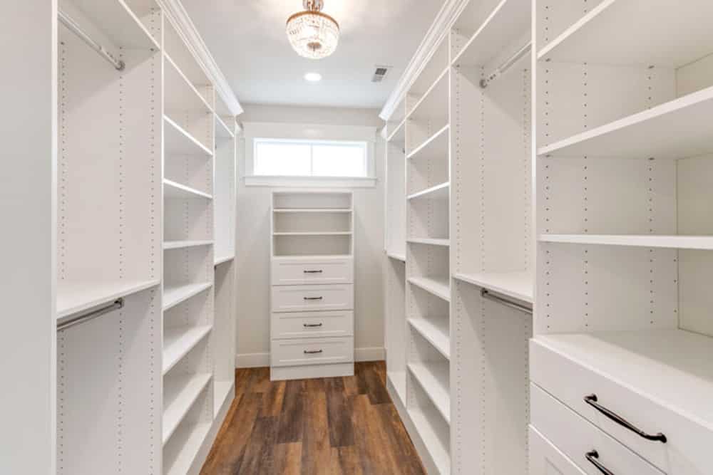 Spacious white walk-in closet with organized shelving and modern lighting.