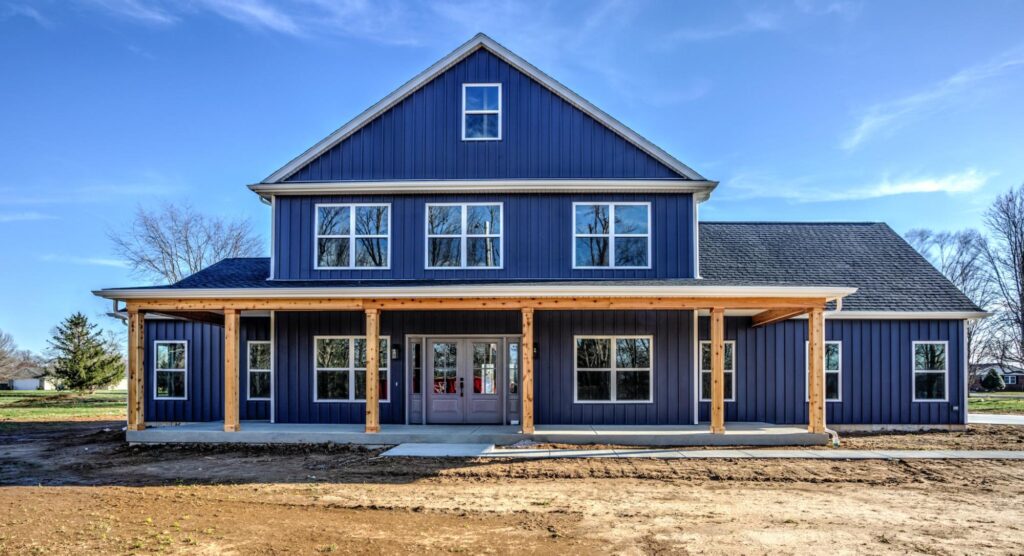 Charming blue house with a welcoming porch and large windows under a bright sky.