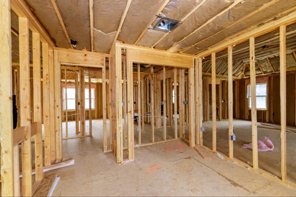 Interior framing process showcasing wooden studs in a partially constructed home.