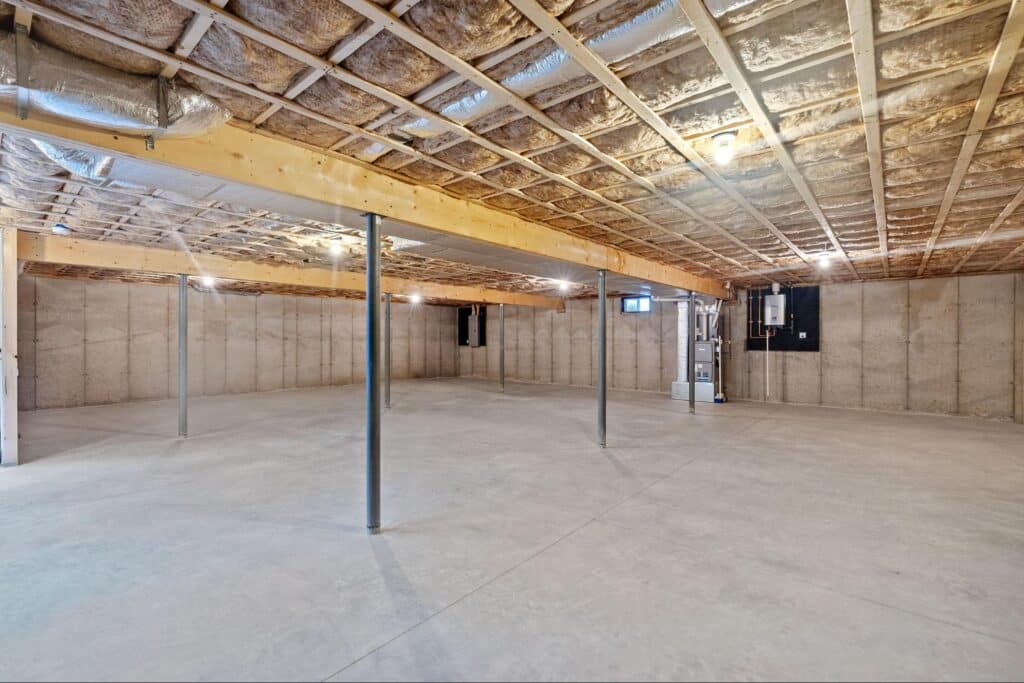 Spacious basement with concrete floor and exposed beams, ideal for storage or renovation.