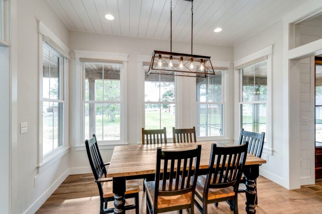 Cozy dining room featuring a wooden table and bright, airy windows.