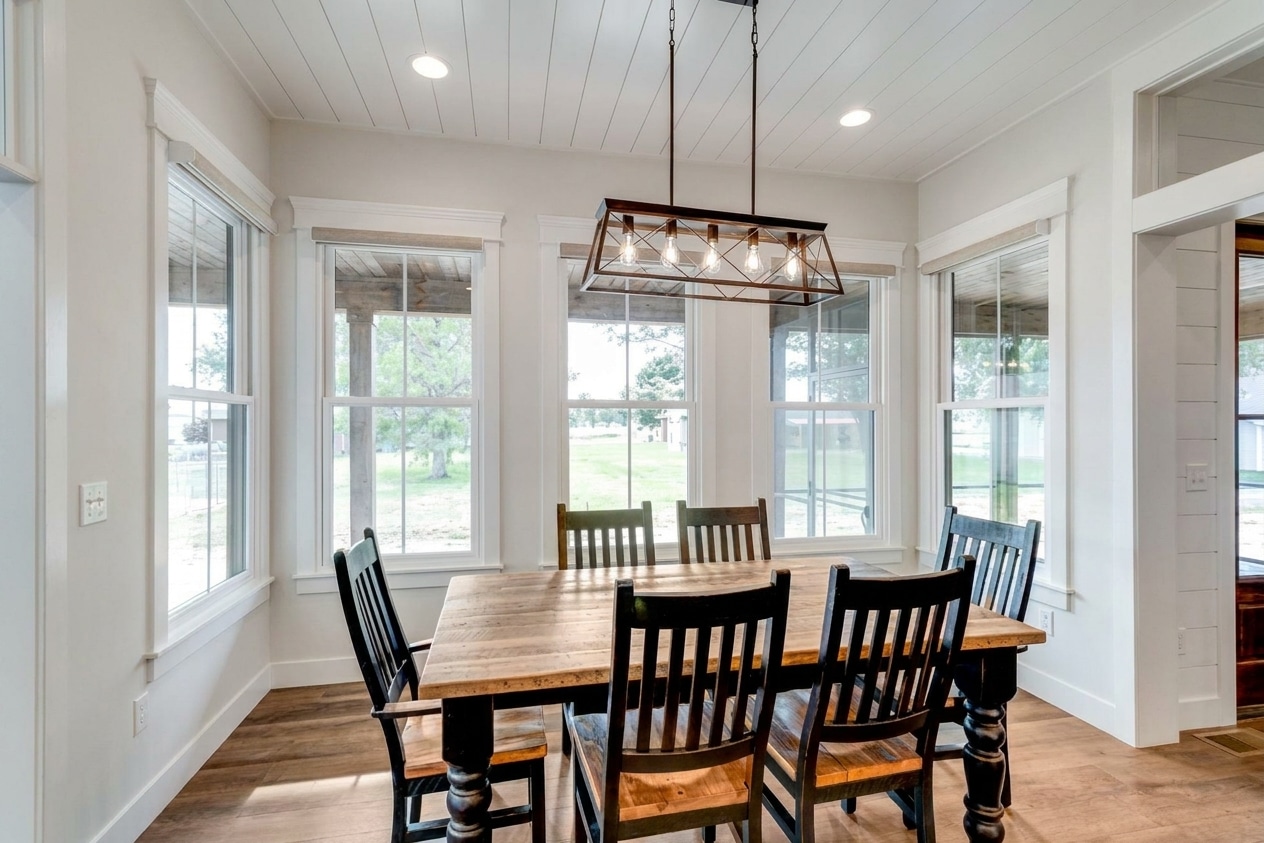 Cozy dining room featuring a wooden table and bright, airy windows.