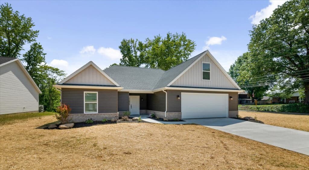 Modern house front view with landscaping, showcasing contemporary design and garage.